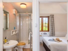 A bathroom with shower and sink beside a bedroom with window and bed at The Hayloft Budock Water near Falmouth
