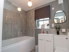 A bathroom with a bathtub, sink, and window at Rosie's Retreat in Filey