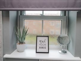 A bathroom window with a plant, sign, and mirror at Rosie's Retreat in Filey