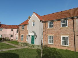 A house with a green door and windows surrounded by grass at Rosie's Retreat in Filey