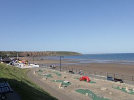 A beach with a mini-golf course and cliffs in the background at Rosie's Retreat in Filey