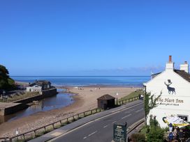 A beach view with The Hart Inn and sea at Woodbine Cottage in Whitby