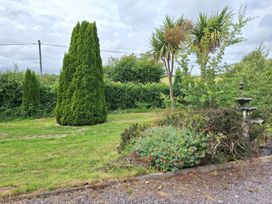 A garden with trees and a fountain at Lilly's Bungalow in Timoleague