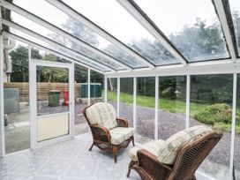 A conservatory with wicker chairs and garden view at Lilly's Bungalow Clonakilty, County Cork