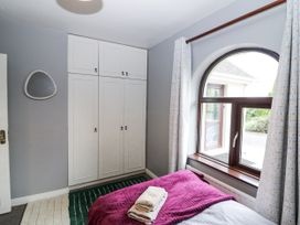 A bedroom with a wardrobe and window at Lilly's Bungalow in Clonakilty, County Cork