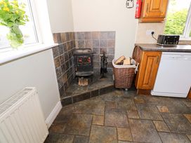 A kitchen with a wood stove, logs, and a dishwasher at CARROWREAGH