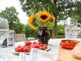 An outdoor dining setup with strawberries and a sunflower at Lakeside Lodge near Witherenden Hill Burwash