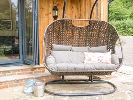 A hanging chair with cushions by a wooden wall at Lakeside Lodge in Witherenden Hill near Burwash