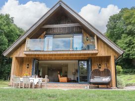 A wooden house with a deck and outdoor furniture at Lakeside Lodge Witherenden Hill near Burwash