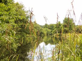 A river surrounded by grass and trees at Lakeside Lodge near Witherenden Hill