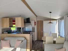 A living room with a sofa and dining area at The Maples, no. 56 St. Austell