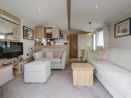 A living room with a sofa and dining area at The Maples, no. 56 Hewas Water near Polgooth