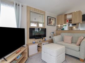 A living room with a television and sofa at The Maples, no. 56 Hewas Water near Polgooth