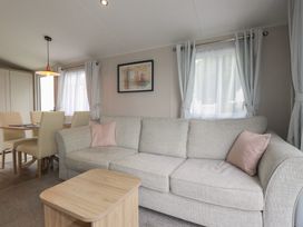 A living room with a sofa and dining area at The Maples, no. 56 Hewas Water near Polgooth