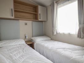 A bedroom with two single beds and curtains at The Maples, no. 56 Hewas Water near Polgooth