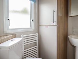 A bathroom with a toilet, sink, radiator, and refrigerator at The Maples, no. 56 Hewas Water near Polgooth