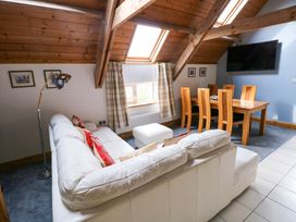 A living room with a sofa and dining area at Pendre Barn in Star near Cenarth