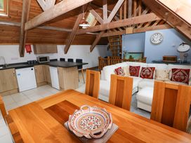 A living room with a kitchen area and dining table at Pendre Barn Star near Cenarth
