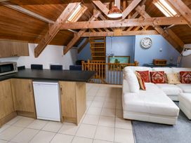 A living room with a kitchen area and a staircase at Pendre Barn Star near Cenarth
