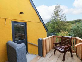 An outdoor deck with a wooden chair and a yellow wall at Pendre Barn Star near Cenarth