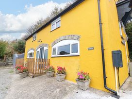 A house with a yellow exterior and flower pots at Pendre Barn Star near Cenarth