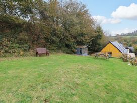A garden with a bench and a shed at Pendre Barn Star near Cenarth