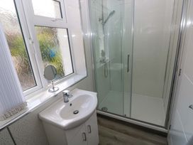 A bathroom with a sink, mirror, and shower at Pinecroft Annex Stepaside near Saundersfoot