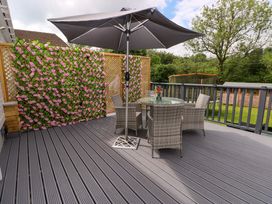 An outdoor deck with a table and chairs under an umbrella at Pinecroft Annex Stepaside near Saundersfoot