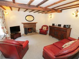 A living room with a fireplace and leather furniture at Fern Cottage 