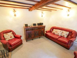 A living room with red furniture and a wooden cabinet at Fern Cottage