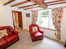 A living room with two red armchairs and a window at Fern Cottage in 