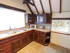 A kitchen with cabinets, sink, and appliances at Fern Cottage