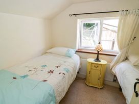 A bedroom with two beds and a yellow side table at Fern Cottage