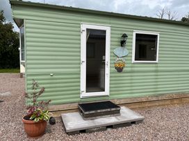 An exterior view of a green structure with a door and window at Sylvan in Builth Wells