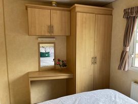 A bedroom with a wardrobe and a desk with a mirror at Sylvan in Builth Wells
