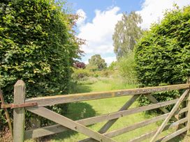 A view through a wooden gate lined with hedges and grass at Uplands House Ledbury