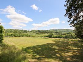 A grassy area with trees and hills under a blue sky at Uplands House in Ledbury