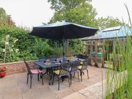 A garden with a dining table and chairs under an umbrella at Uplands House Ledbury