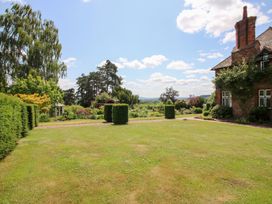 A garden with grass, hedges, and trees at Uplands House Ledbury