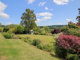 A garden with flower beds and a shed at Uplands House in Ledbury