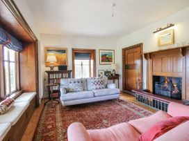 A living room with a sofa and bookshelf at Uplands Dowerhouse in Wellington Heath near Ledbury