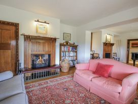 A living room with a fireplace, bookshelves, and sofas at Uplands Dowerhouse in Wellington Heath near Ledbury