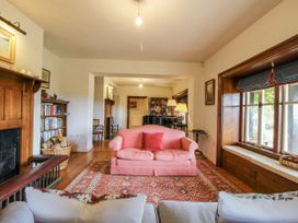 A living room with a pink sofa and bookshelf at Uplands Dowerhouse Wellington Heath near Ledbury