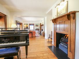 A living room with a piano and fireplace at Uplands Dowerhouse in Wellington Heath near Ledbury