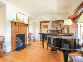 A living room with a grand piano and fireplace at Uplands Dowerhouse Wellington Heath near Ledbury