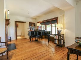 A living room with a piano and bookshelf at Uplands Dowerhouse Wellington Heath near Ledbury