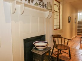 A hallway with a fireplace and wooden chair at Uplands Dowerhouse Wellington Heath near Ledbury
