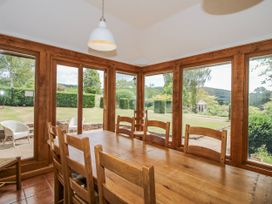 A dining room with a wooden table and chairs overlooking a garden at Uplands Dowerhouse Wellington Heath near Ledbury