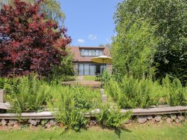 A garden with ferns and a house with an umbrella at Uplands Cottage in Ledbury