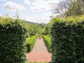 A garden with hedges and a pathway leading to a flowerpot at Uplands Cottage Ledbury